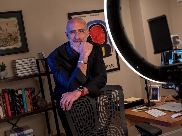 Arthur Brooks stands behind a chair in his office, smiling