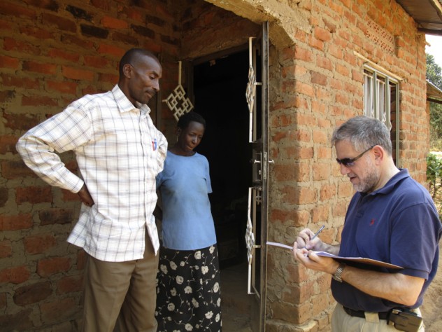 Photograph by Elizabeth Gudrais University Provost Steven Hyman, who visited Uganda in 2009 to learn about SHIP and other projects in Mbarara, signs the guest book at Nshemereirwe's house as Musinguzi looks on.