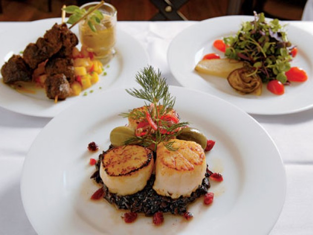 Scallops atop black sticky rice; behind, beef satay and baby greens
