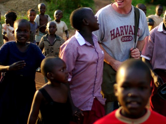 Photograph by Ian MacLellan Christopher Higgins ’10 walks through Busia, Uganda, in July with residents of the New Hope orphanage (wearing the crimson-and-white New Hope school uniform) and children from the community.