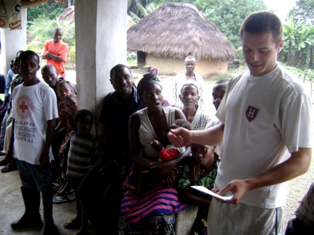 Courtesy of David Sengeh Using notes to bolster his command of Mende, the local language, Sam Slaughter ’09 introduces himself and the GMin team to villagers.