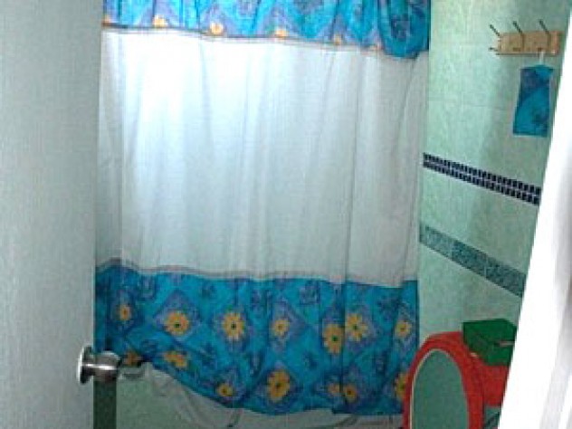 The Huertas' bathroom displays color-coordinated finishings: they replaced the toilet and sink and tiled the walls, floor, and bathtub.