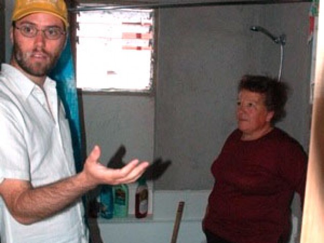 Ortega (right) talks with ELEMENTAL project manager Gonzalo Arteaga in the bathroom of her home. Despite the unfinished walls, residents are pleased that the bathroom in each unit has a bathtub and a window that opens.