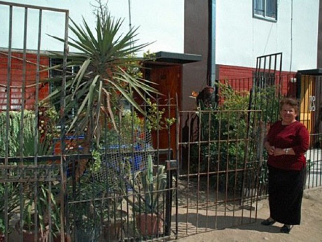 Ortega stands in front of her home. She fenced in her yard and filled it with plants, which she sells to support herself and her two-year-old grandson.