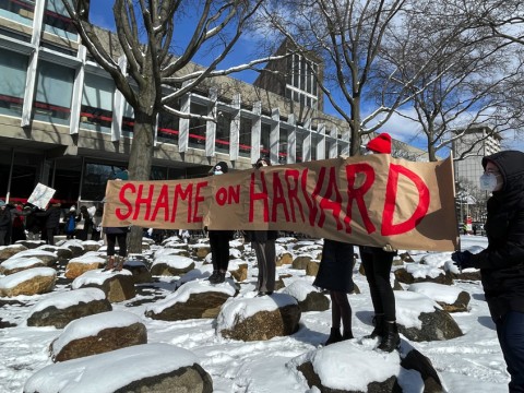 Demonstrators hold up a sign that reads, "Shame on Harvard." 