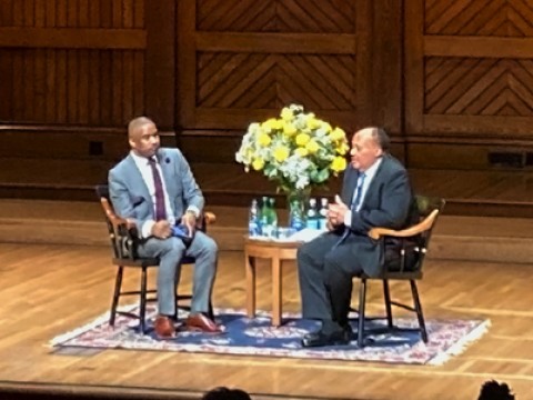 Martin Luther King III and Brandon Terry seated in chairs on a large auditorium stage