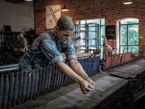A replica of a textile mill shows life-like statues of workers. 