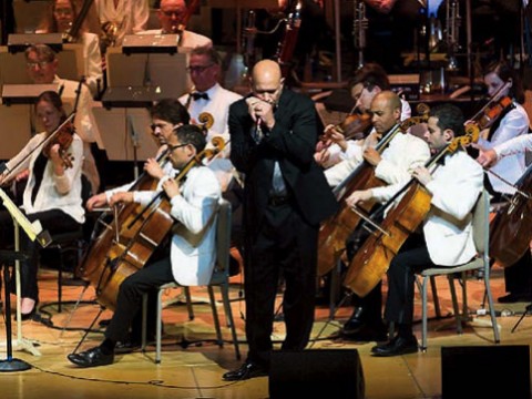 Johnson plays his harmonica with the Boston Pops orchestra behind him.