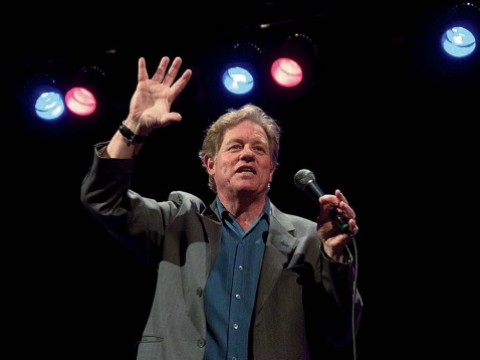 Jimmy Tingle holding a microphone and performing on stage 