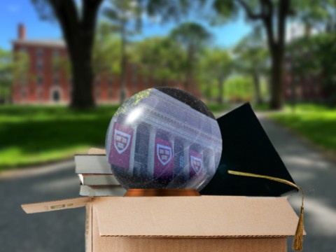Moving out box in Harvard Yard with a Harvard snow globe, graduation cap, and books