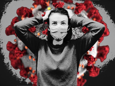 A person wearing a mask standing in front of the COVID virus