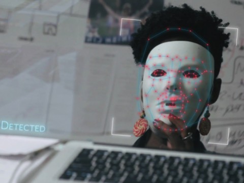 Joy Buolamwini dons a white mask in order to be visible to facial recognition software in the film Coded Bias.