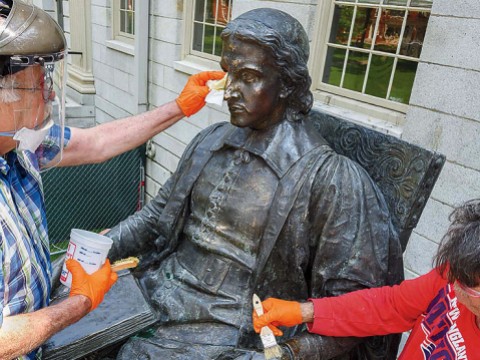 Conservators from Skylight Studios work on the John Harvard statue