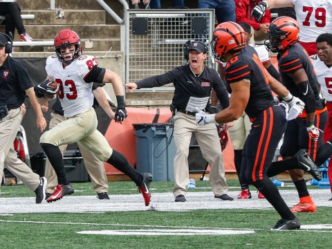 Harvard wide receiver runs up field, away from Princeton defenders.