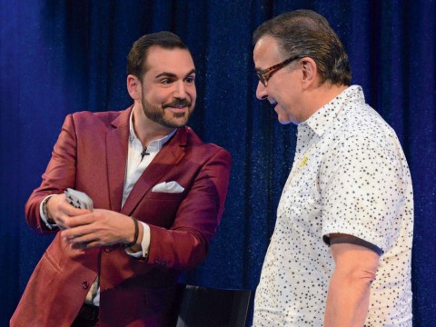 A magician and comedian doing a card trick with an audience member