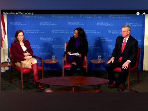 The three speakers are seated on stage at Harvard's JFK Forum.