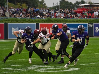 Holy Cross player has ball and Harvard players try to tackle with additional Holy Cross players in pursuit