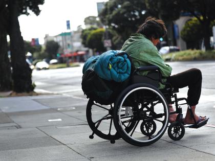 research for origin of life A man in a wheelchair with a rolled-up sleeping bag strapped to the back