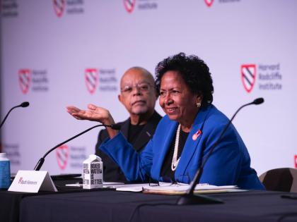 Ruth Simmons sits at a table on the stage with Henry Louis Gates, Jr. 