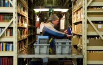 Nearly half of Harvard’s collection is housed at the Harvard Depository, a marvel of efficient off-campus storage. Library assistant Carl Wood reshelves books in the 30-foot-high, 200-foot-long stacks.