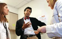 Gawande speaks with patient Ericka Webb (right) at a post-surgical follow-up. Medical student Devon Quasha ’02, J.D. ’06, is at left..