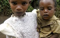 A war-affected girl in Rwanda cares for her younger sibling.