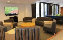 Recent renovations in Old Quincy, now renamed Stone Hall: a new community room with couches, flat-screen TV, a new kitchen, and a below-grade terrace outside the glass doors