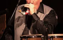 Percussionist Manolo Badrena playing a percussion instrument.