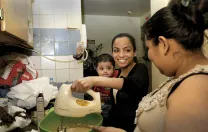 Katty Morocho (center), a social worker for Little Sisters, teaches client Zenaida Vega to bake a cake while Vega’s nephew, Miguel, looks on. Vega hopes to find work at a bakery.