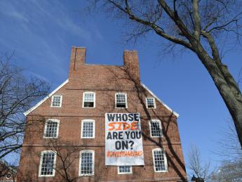 A Divest Harvard sign hangs from the windows of Mass. Hall.