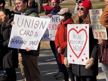 Organizers hold signs advocating for a union of non-tenure-track workers during a February rally in Harvard Yard