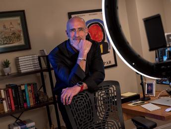Arthur Brooks stands behind a chair in his office, smiling