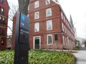 sign in the foreground reading "Massachusetts Hall" with Massachusetts Hall at Harvard University in the background