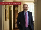 Alan M. Garber in a room in Massachusetts Hall with a red banner "The View from Mass Hall"