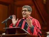 Rakesh Khurana, wearing a red doctoral robe, speaking at a podium 