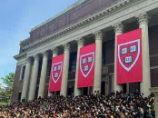 Commencement flags at Widener with students gathered on steps