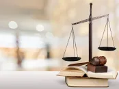 Scales of justice and a gavel resting on open law books with a blurred courtroom background.