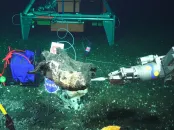 A robotic arm interacting with an underwater object on the ocean floor.