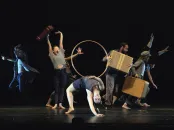 A dynamic dance performance featuring multiple performers engaging with props on stage.