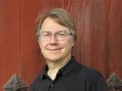 Harvard's Andrew Knoll stands smiling at the camera, wearing a black shirt