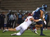 Columbia player is tackled from behind by a Harvard defender during a play.
