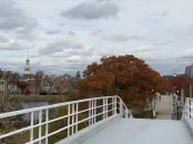 View from a bridge with autumn trees and a cloudy sky in the background.