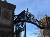Wrought iron gate opening against a bright blue sky, showcasing intricate designs.