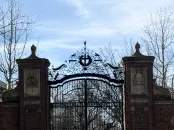 Brick entrance gates with a church in the background and snow on the ground.