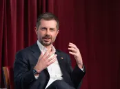A man in a dark suit gestures passionately while speaking at an event.