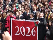 A large group of people poses together, holding a banner for the year 2026.