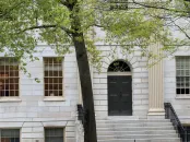 University Hall building facade with a dark door, large windows, and a tree nearby.