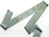 A long, patterned fabric ribbon in shades of blue and green, draped on a white background.