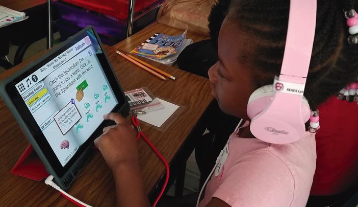 essay about the benefits of having a pet A young girl with pink headphones uses a tablet for an educational reading game at a classroom desk.
