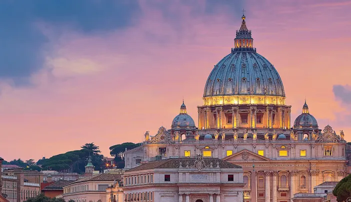 St. Peter's Basilica at sunset, illuminated by purple and orange sky reflections in the river.